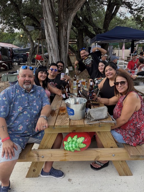 Friends at a picnic table with vendor booths behind them at Rocklobster Fest, Josabi's, Helotes, Texas